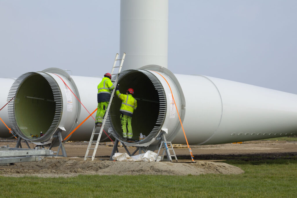 engineers working on the blade of a wind turbine before it is erected.