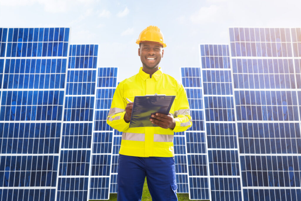 a man in a hard hat and hi-viz jacket standing in front of solar panels