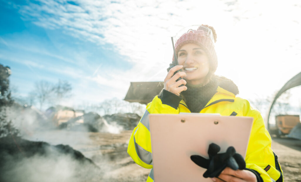 A female manager of a biomass plant using her radio and carrying a clipboard