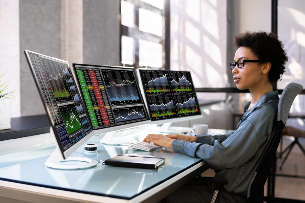 An African American woman sat at a desk with several computer monitors