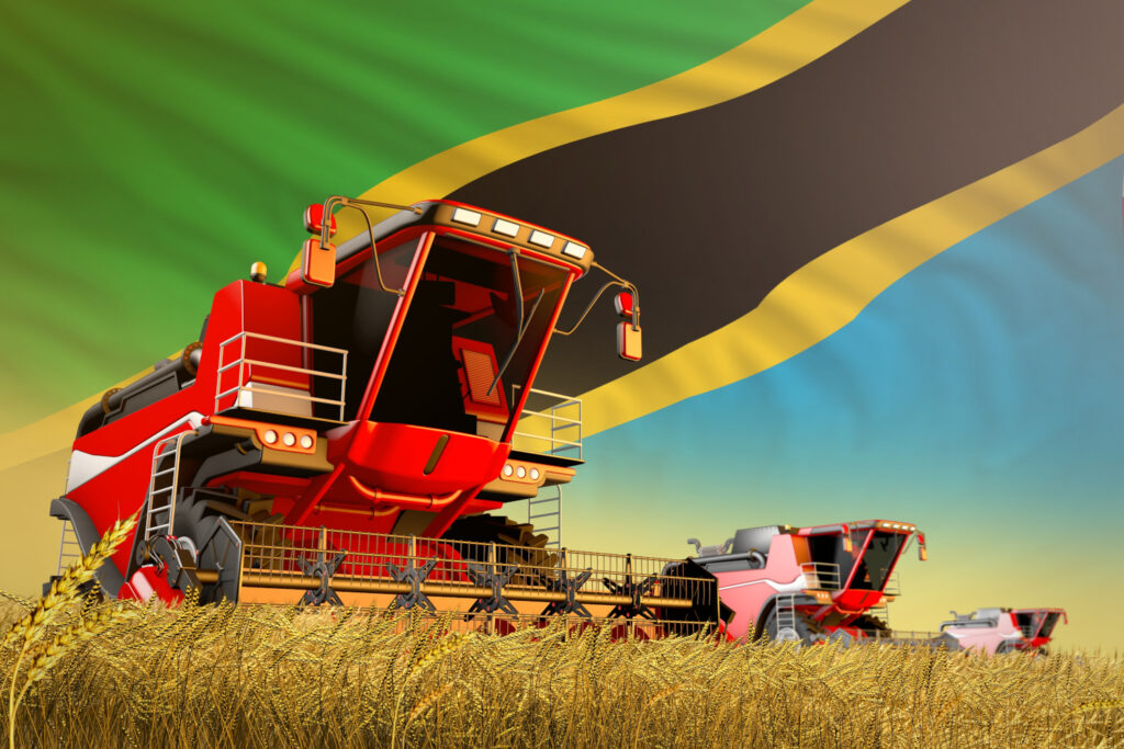An image of a combine harvester working on a crop with the tanzanian flag in the background